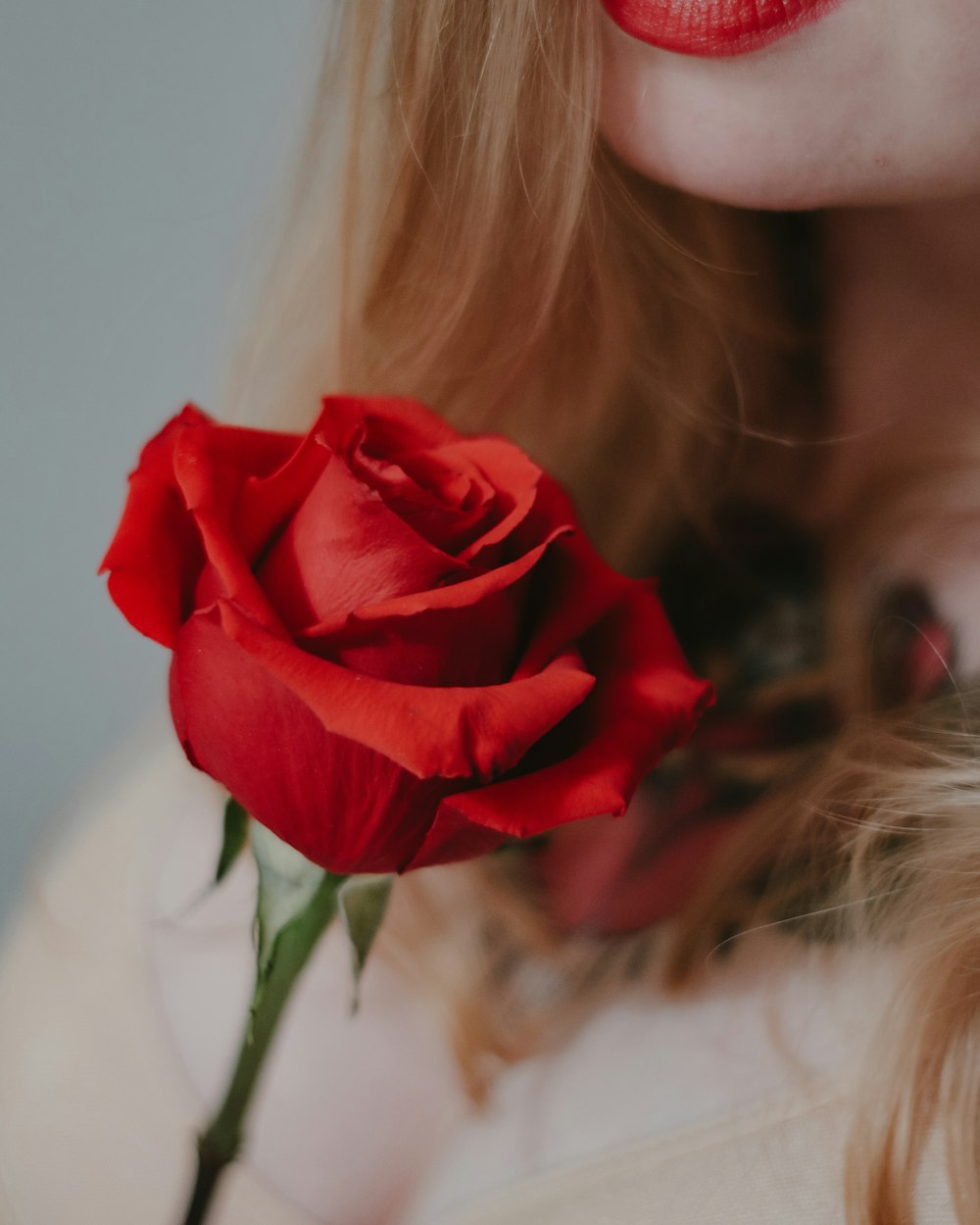 女性の顔に赤いバラ