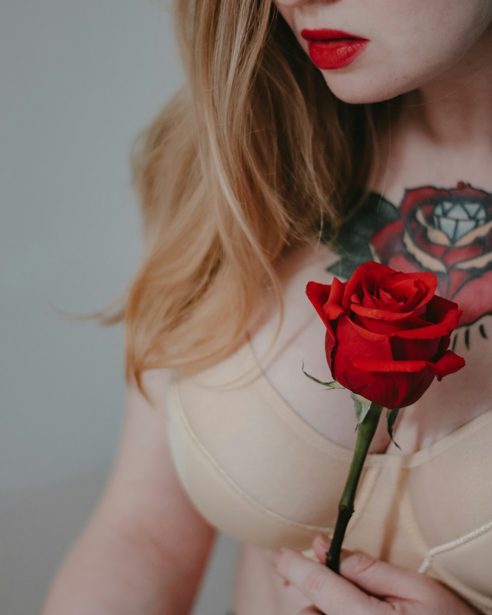 woman in white tank top holding red rose