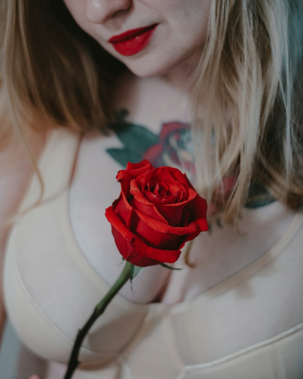 赤いバラを持った白いタンクトップの女性