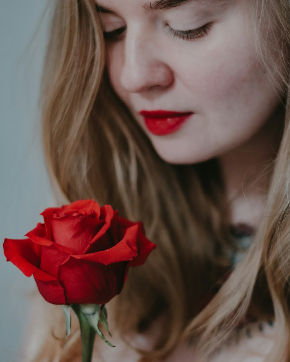 Femme tenant une rose rouge en gros plan