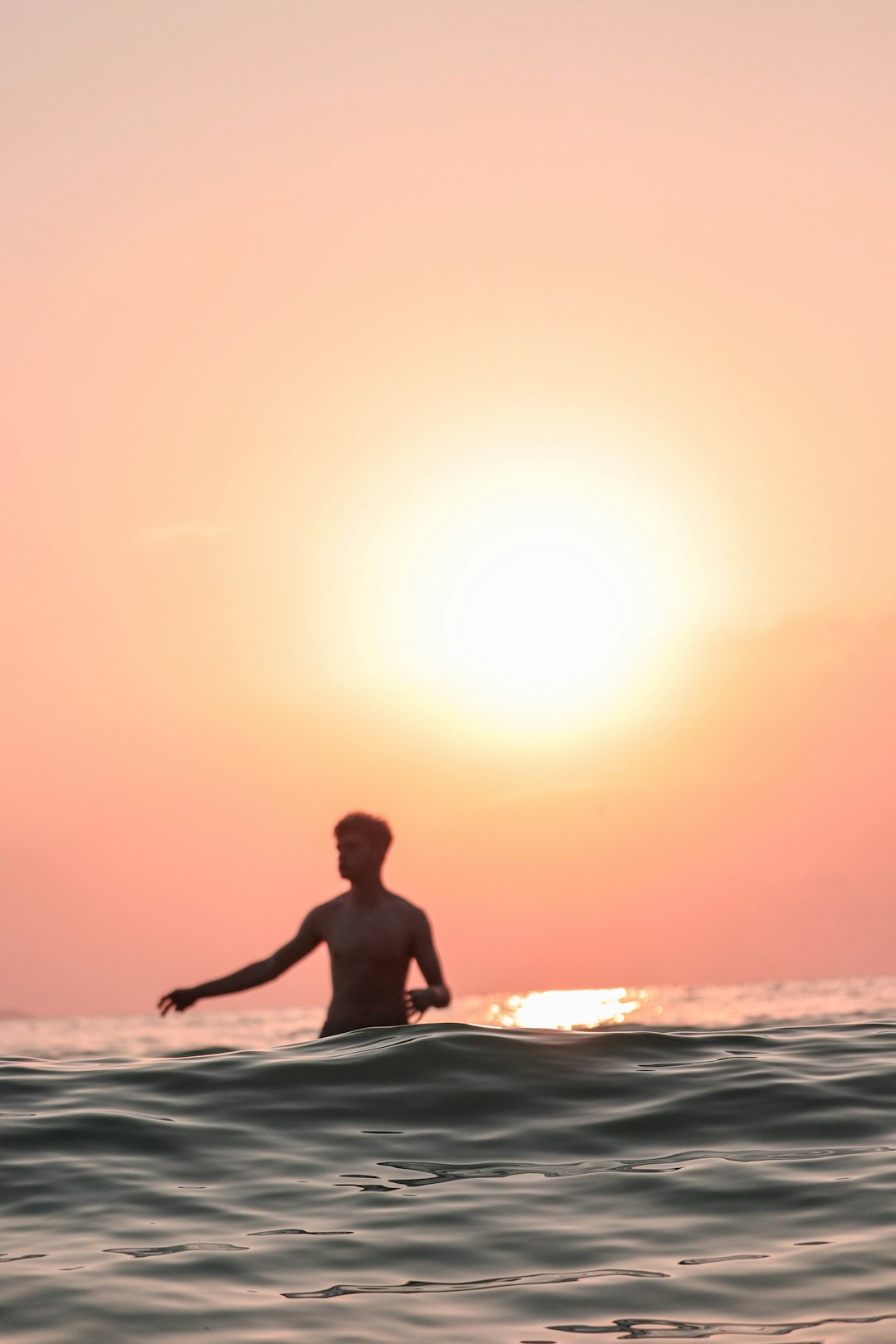 man in black shorts surfing on sea during sunset