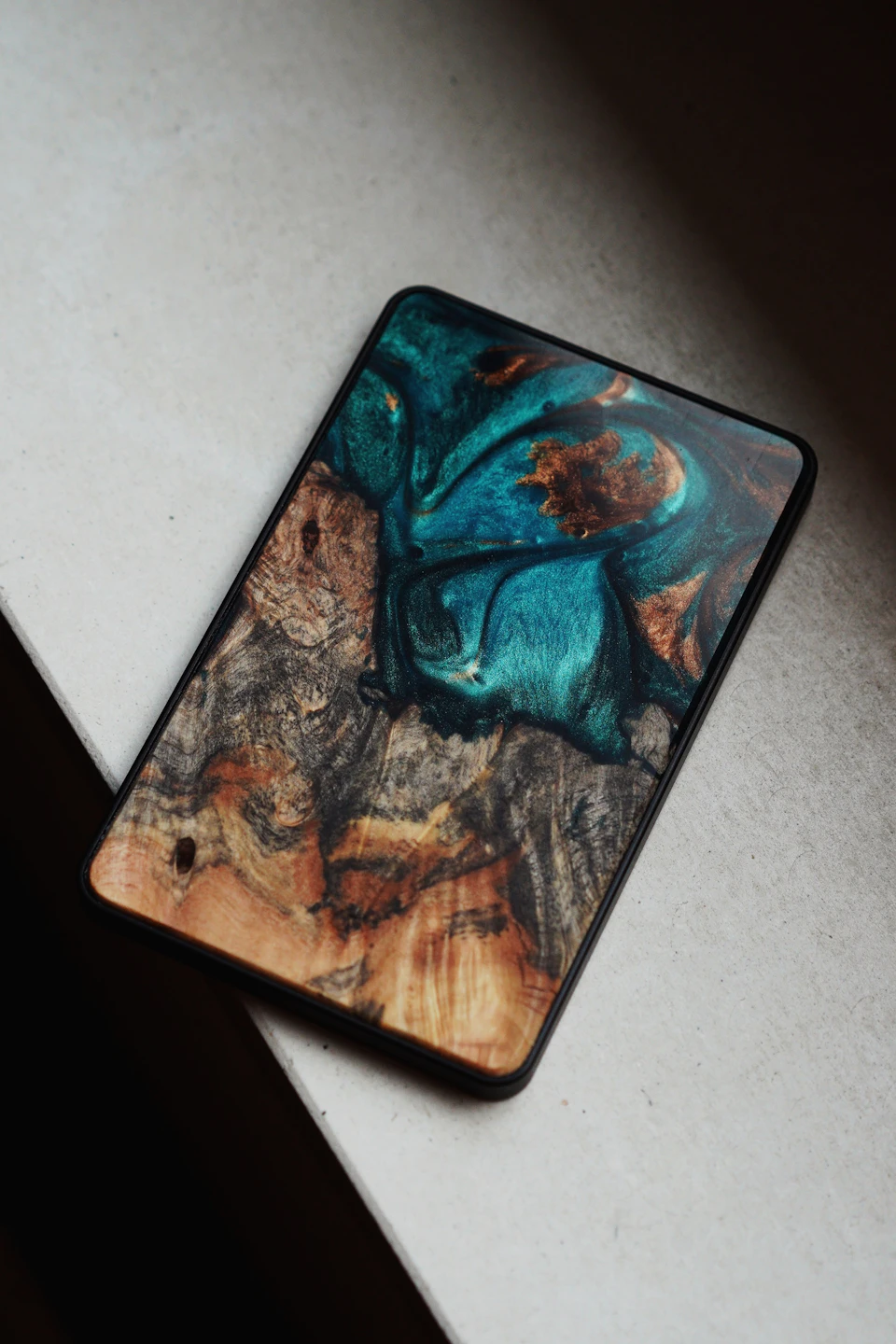 The image shows a small, square-shaped electronic device with a vibrant blue and brown color scheme. The device is resting on a white surface, possibly a table or countertop. The device appears to be a phone case, designed for protection and style.