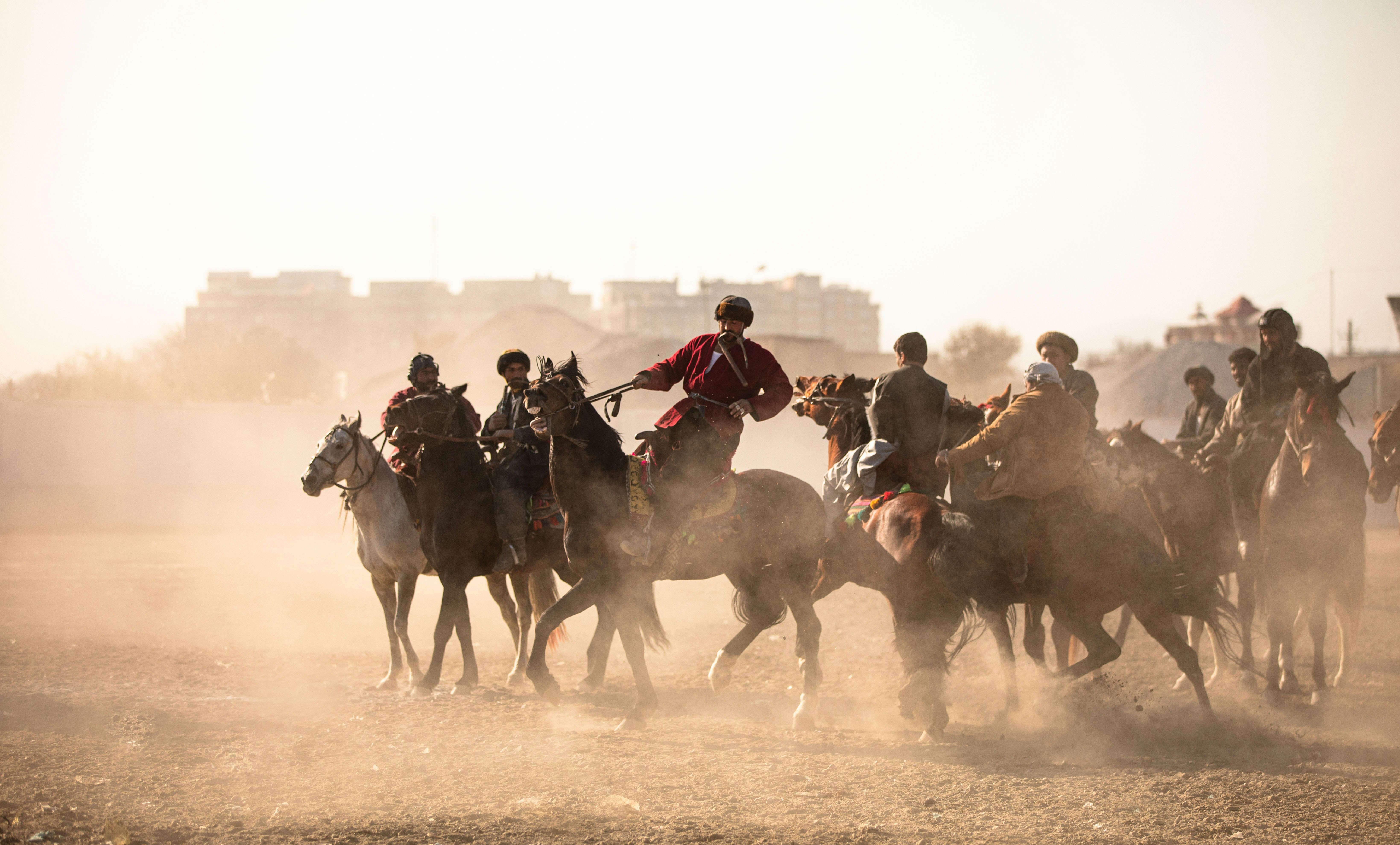 people riding horses on brown sand during daytime