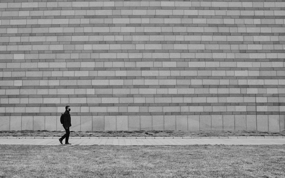 grayscale photo of person walking on sidewalk