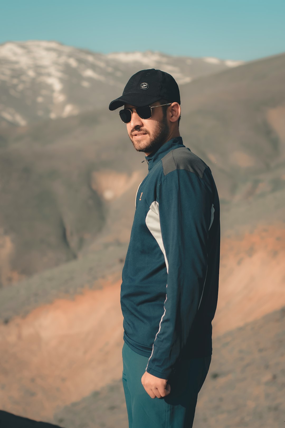 man in blue dress shirt and black pants wearing black cap