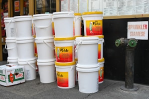 Buckets of waterproofing products lined up neatly in a store aisle