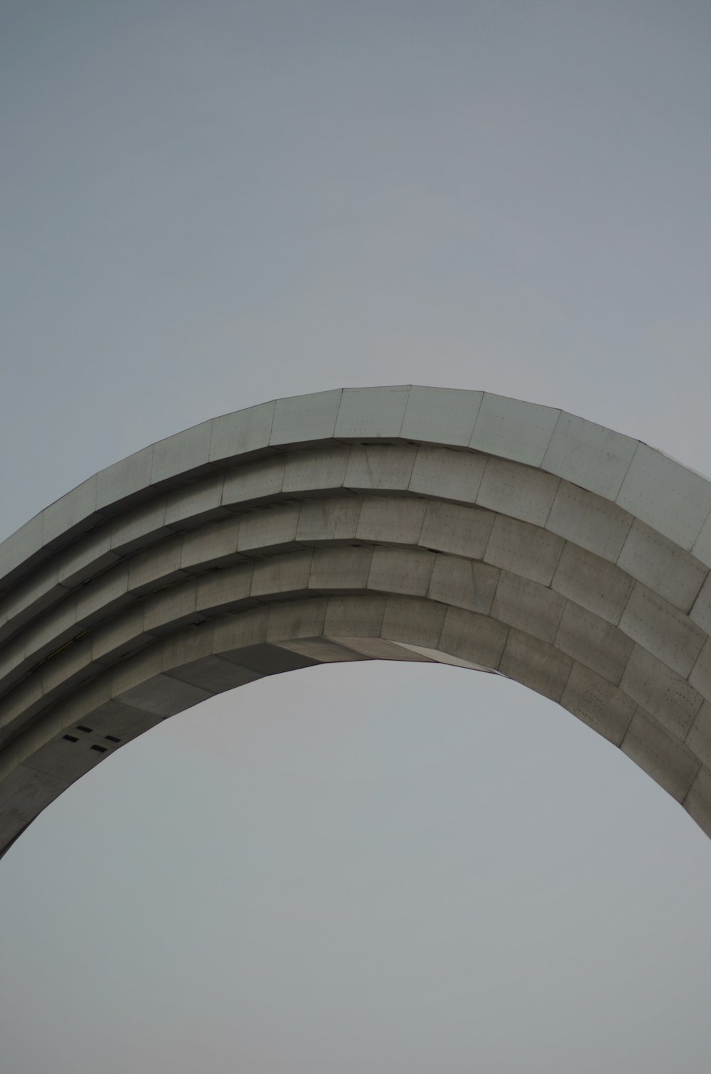 an airplane flying in the sky over a large arch