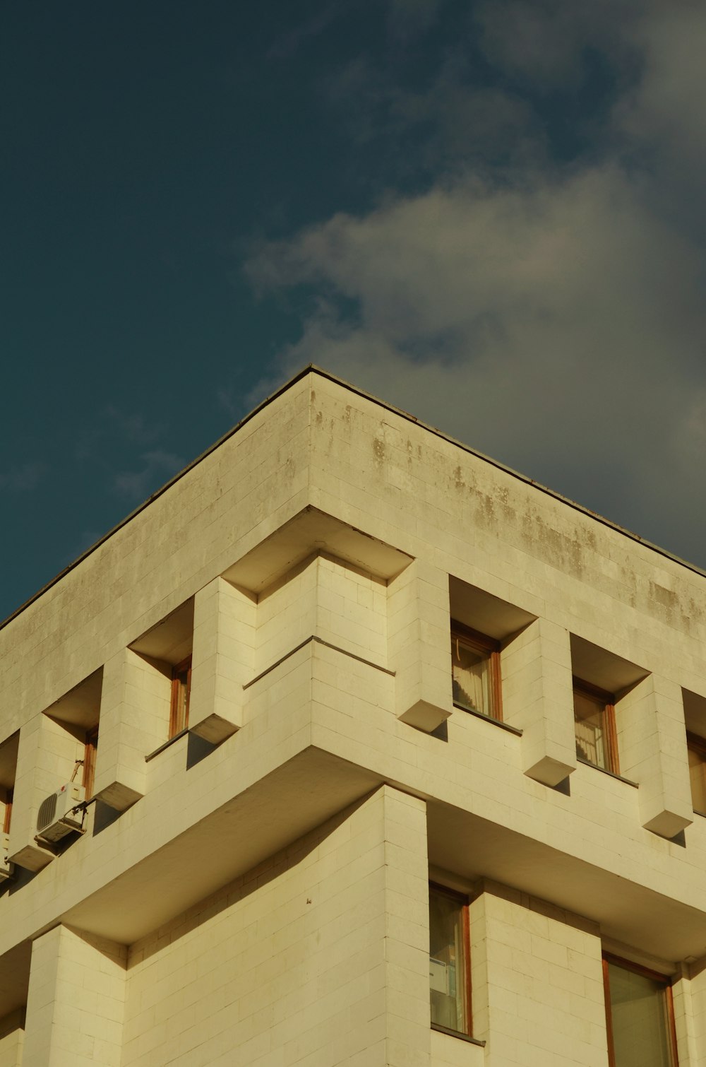 a tall white building with windows and a sky background