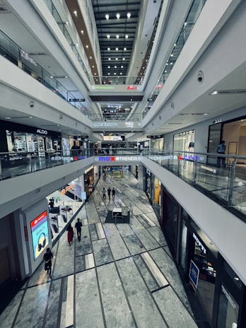 An aerial view of a modern shopping mall with various brand outlets and busy walkways.