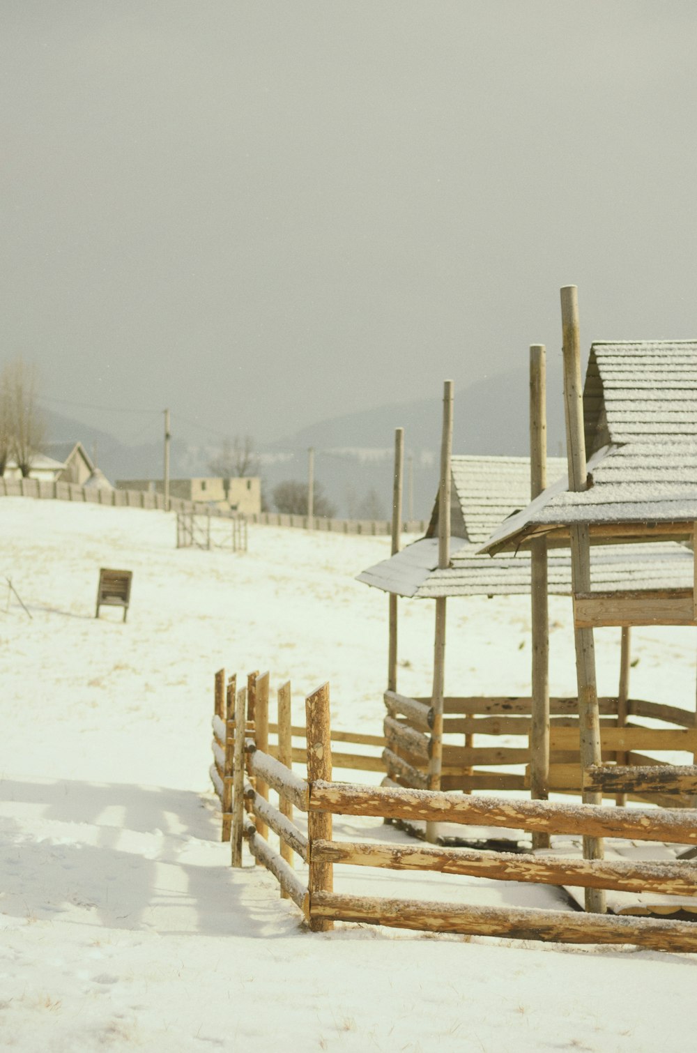 a wooden fence in the snow with a building in the background