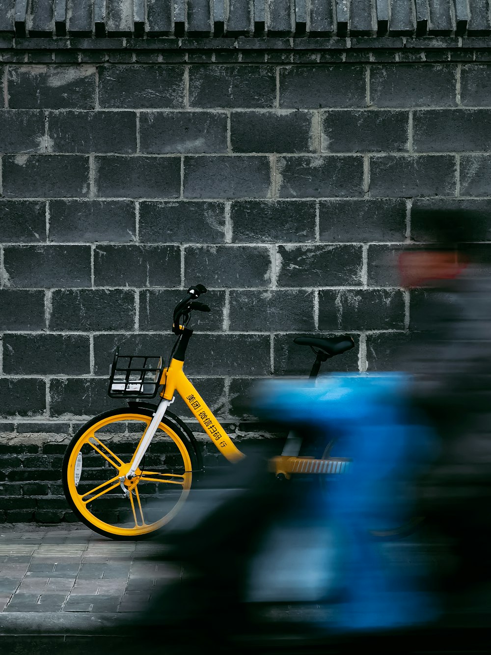 yellow bicycle leaning on brick wall