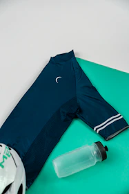 Official race kit laid out on a dark ocean-blue background with turquoise accents.