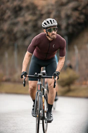 Bakti cycling on a scenic road, wearing triathlon gear and a focused expression.