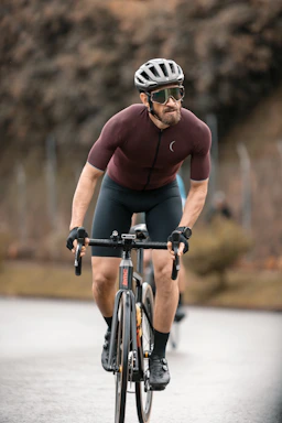 Bakti cycling on a scenic road, wearing triathlon gear and a focused expression.
