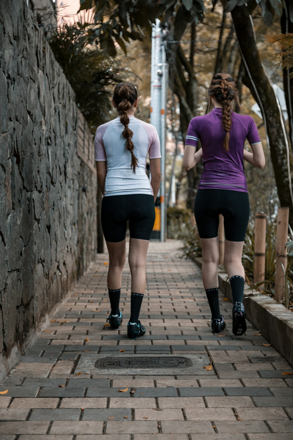 2 women walking on wooden bridge during daytime