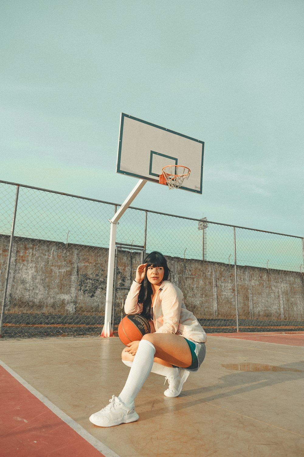 woman in white shirt sitting on basketball court