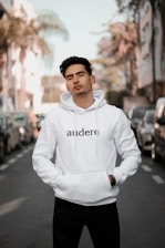 man in white pullover hoodie standing on road during daytime