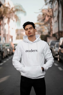 man in white pullover hoodie standing on road during daytime