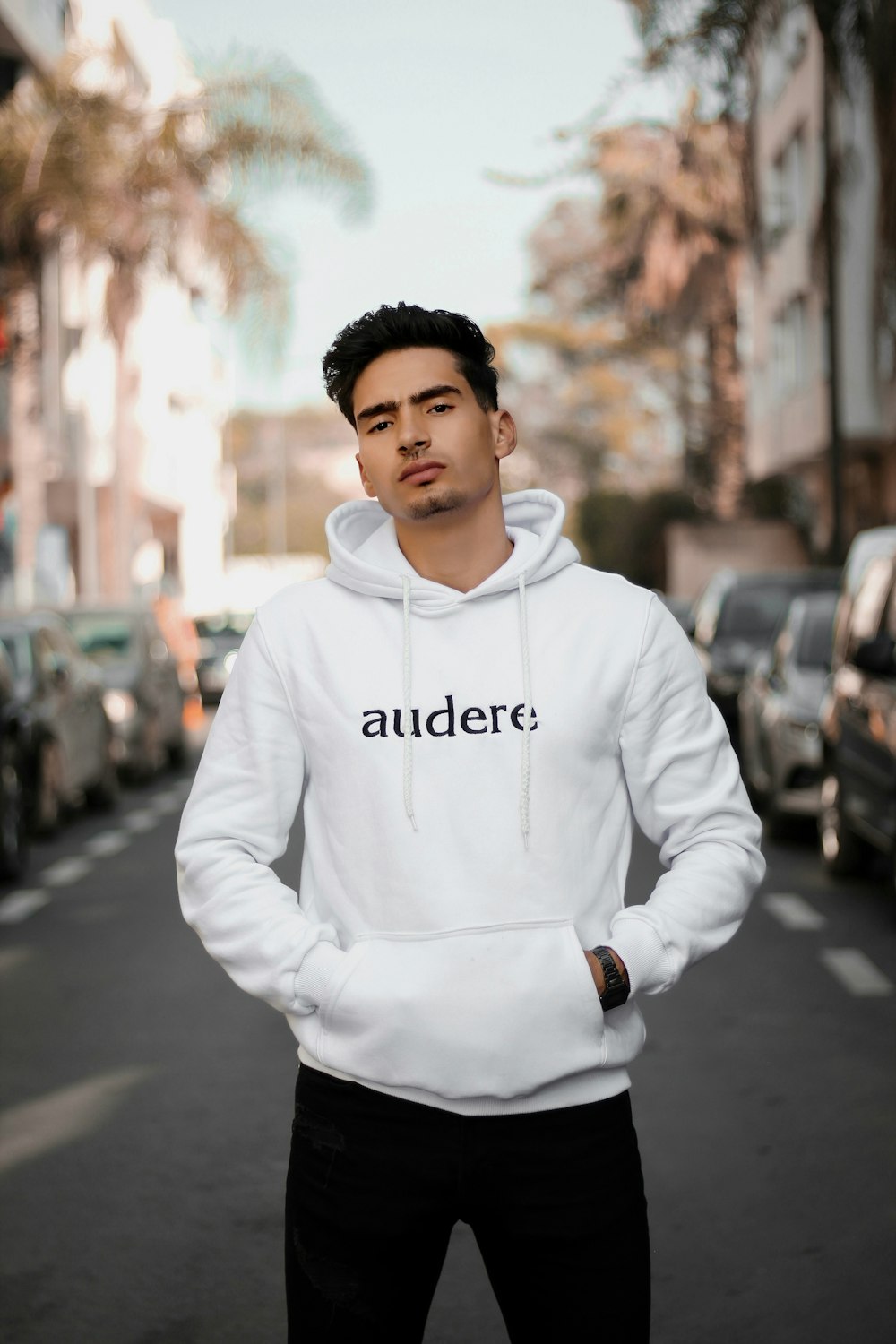 man in white pullover hoodie standing on road during daytime