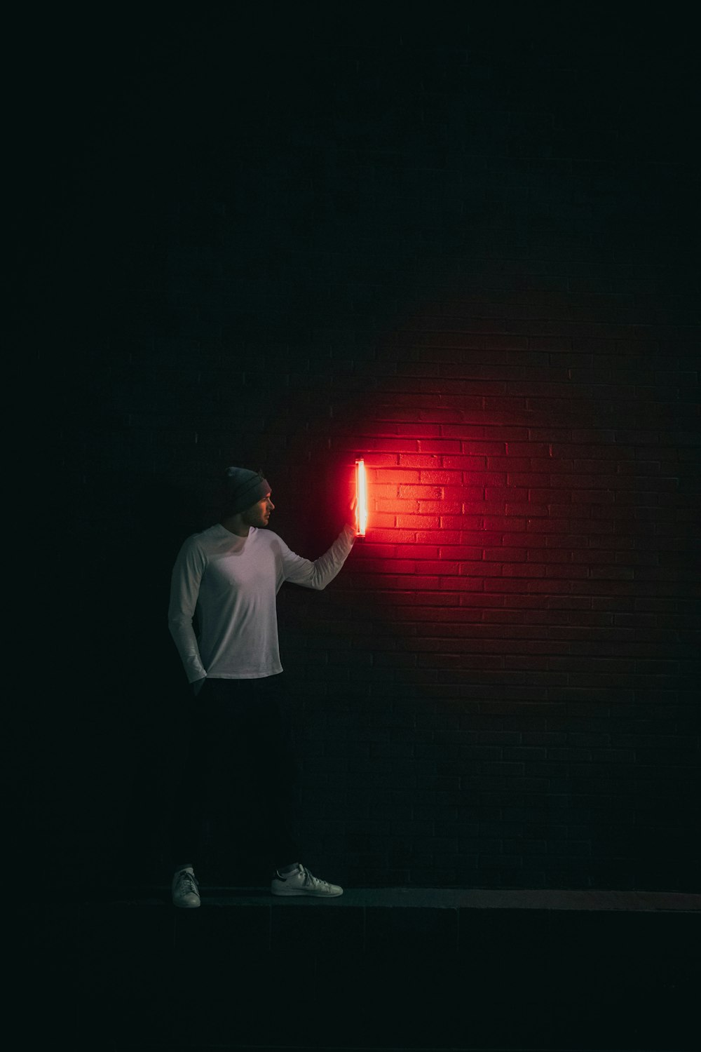 man in white shirt standing in front of red light