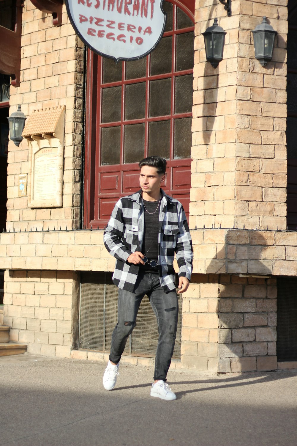 man in black and white striped long sleeve shirt standing beside brown brick wall