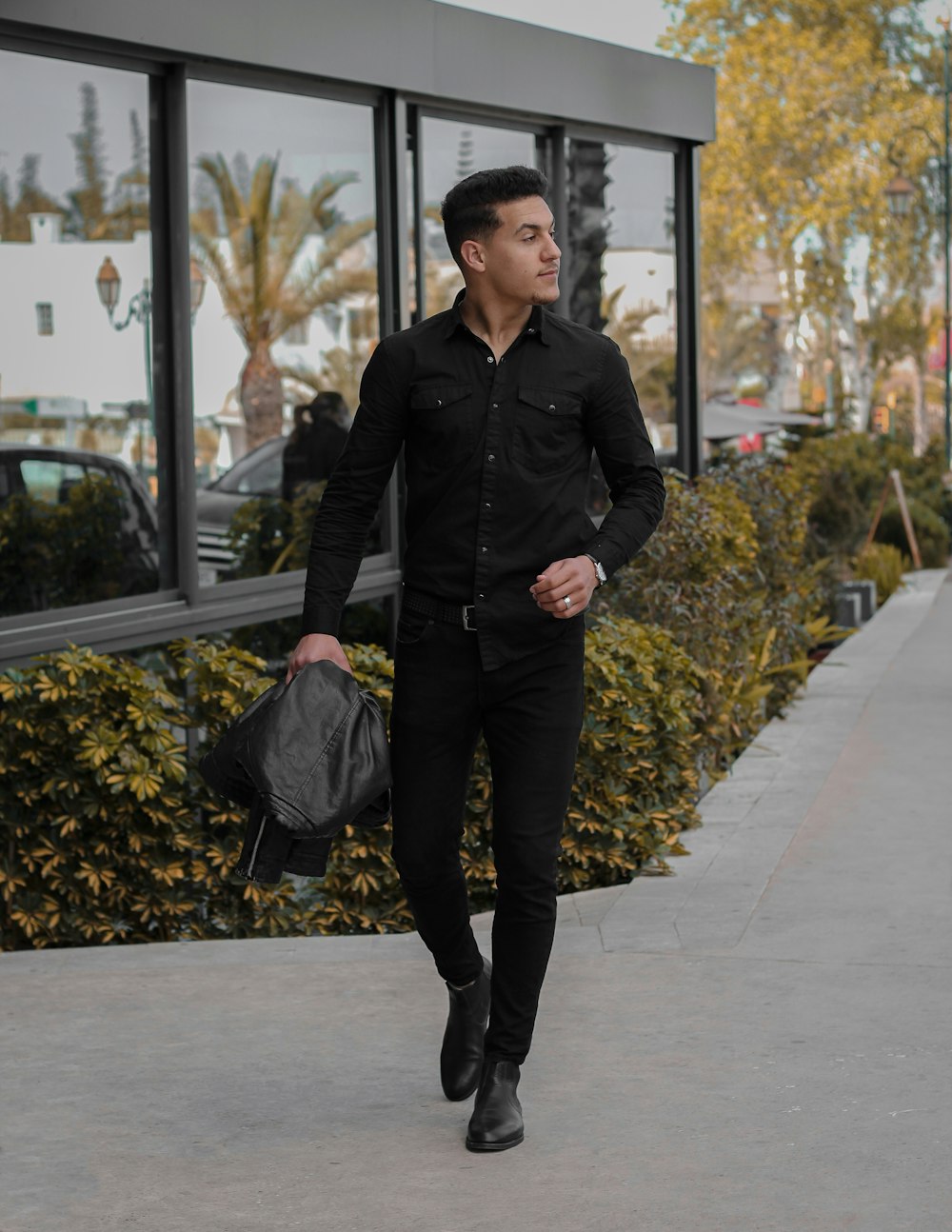 man in black coat holding black plastic bag