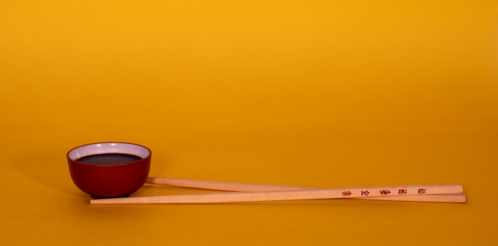 baguettes en bois marron sur bol en céramique rouge et noir
