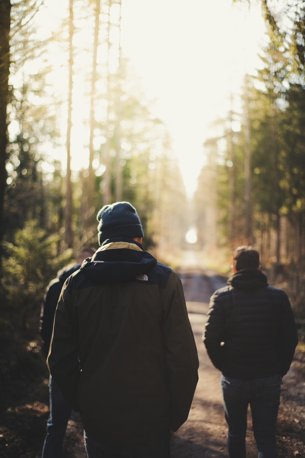 man in black jacket and black knit cap standing in front of green trees during daytime