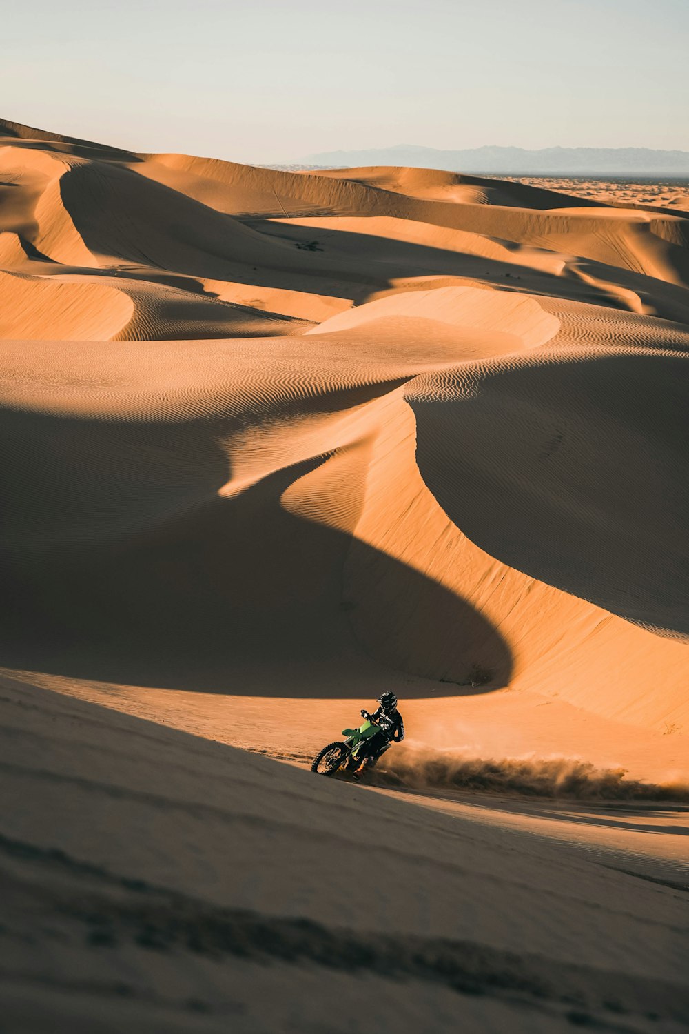 pessoa que monta a motocicleta no deserto durante o dia