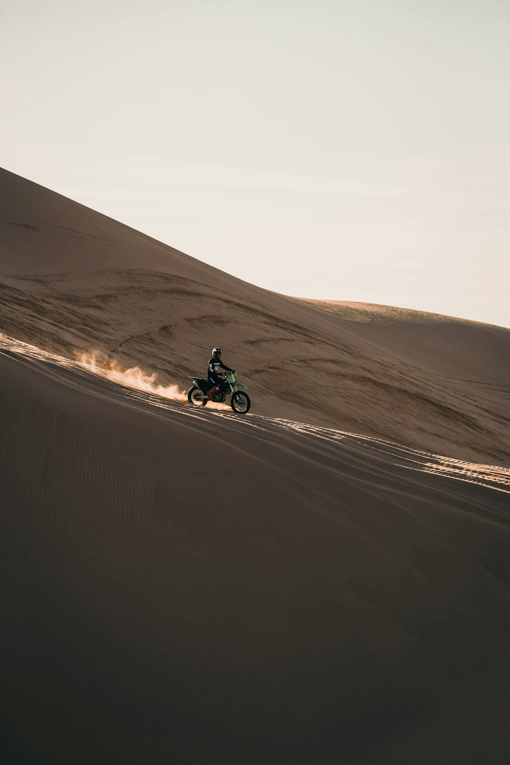 茶色の砂浜にバイクに乗る男