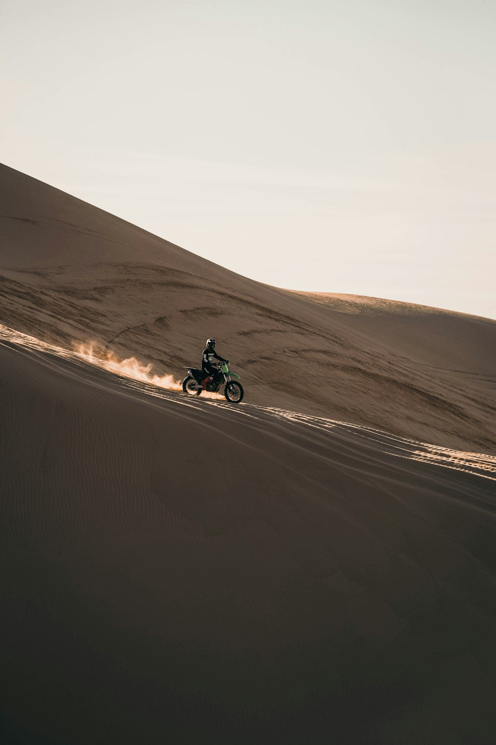 homme conduisant une moto sur du sable brun