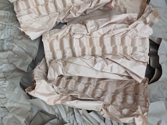 Crumpled brown paper with a textured, ribbed pattern is scattered across the surface. The paper appears to be used for packaging or cushioning, providing a layered and uneven appearance.