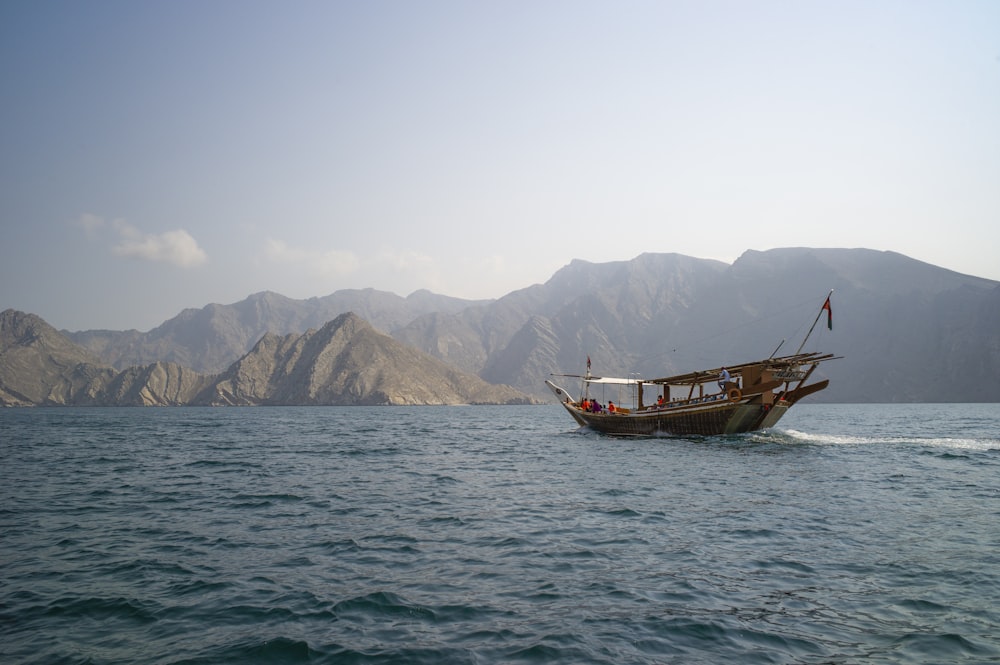 barca marrone sul mare vicino alla montagna durante il giorno