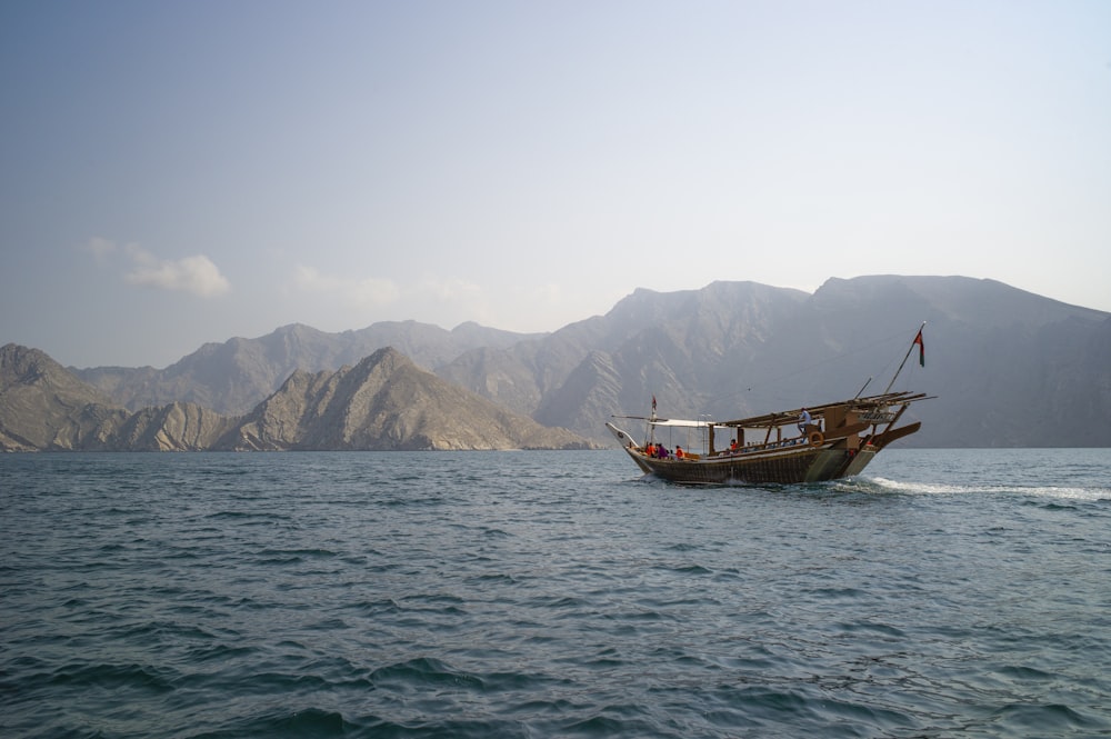 brown boat on sea near mountain during daytime