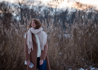 woman in gray scarf standing on brown grass field during daytime