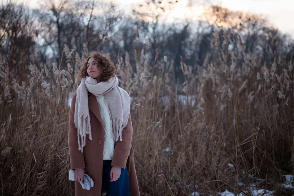 woman in gray scarf standing on brown grass field during daytime