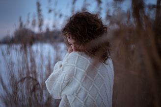 woman in white knit scarf standing on snow covered field during daytime