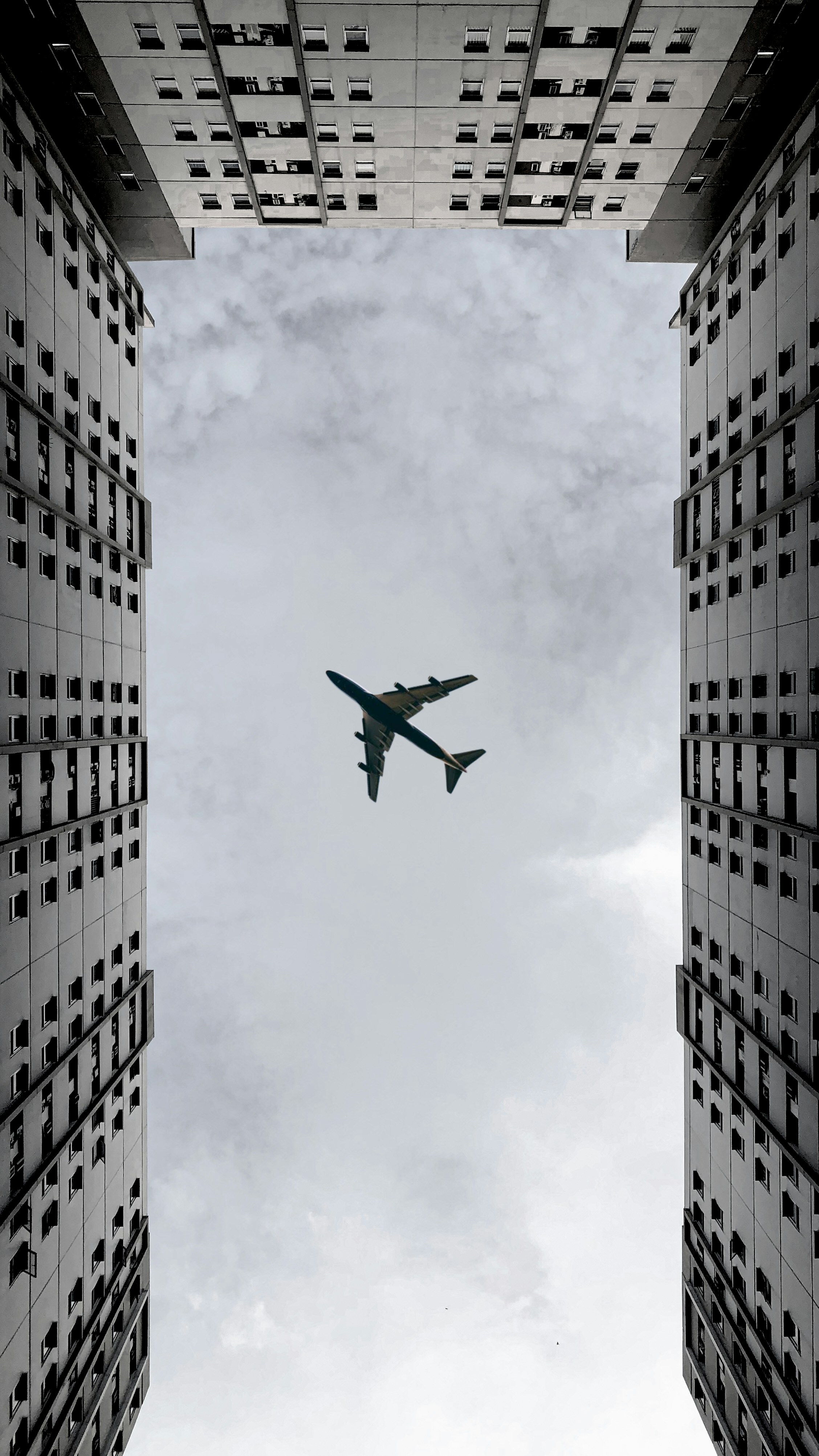 airplane flying over the building during daytime photo Free Grey