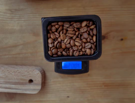 Digital kitchen scale measuring coffee beans on a wooden table.