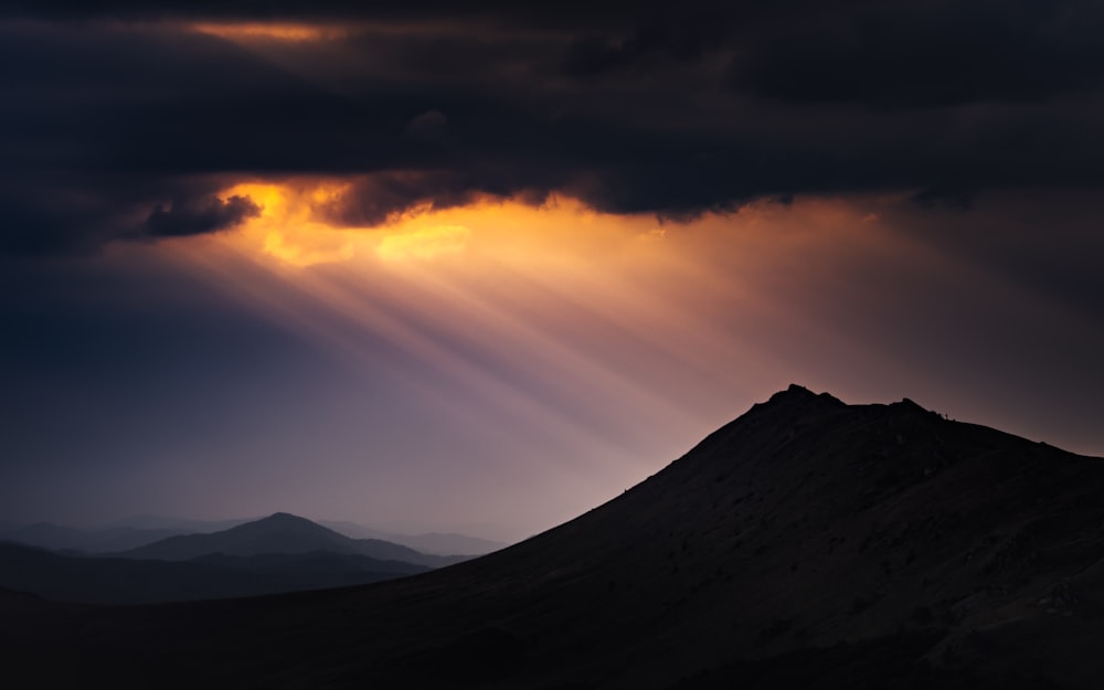 silueta de montañas bajo cielo nublado durante la puesta del sol