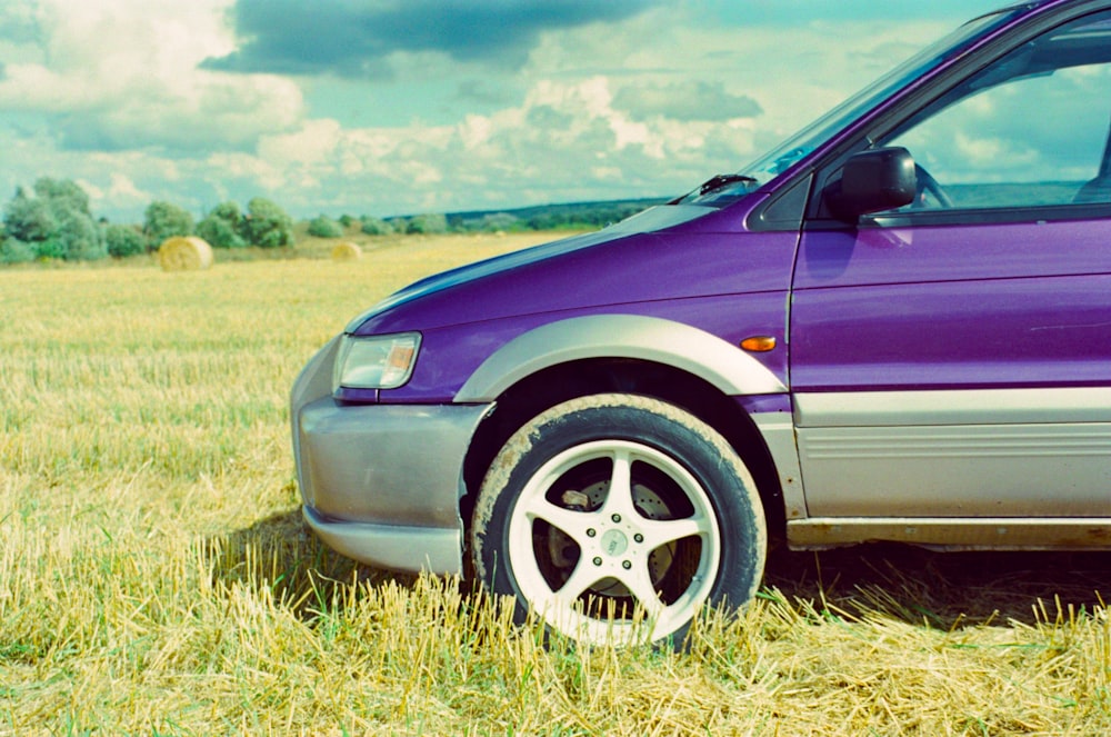 purple car on green grass field during daytime