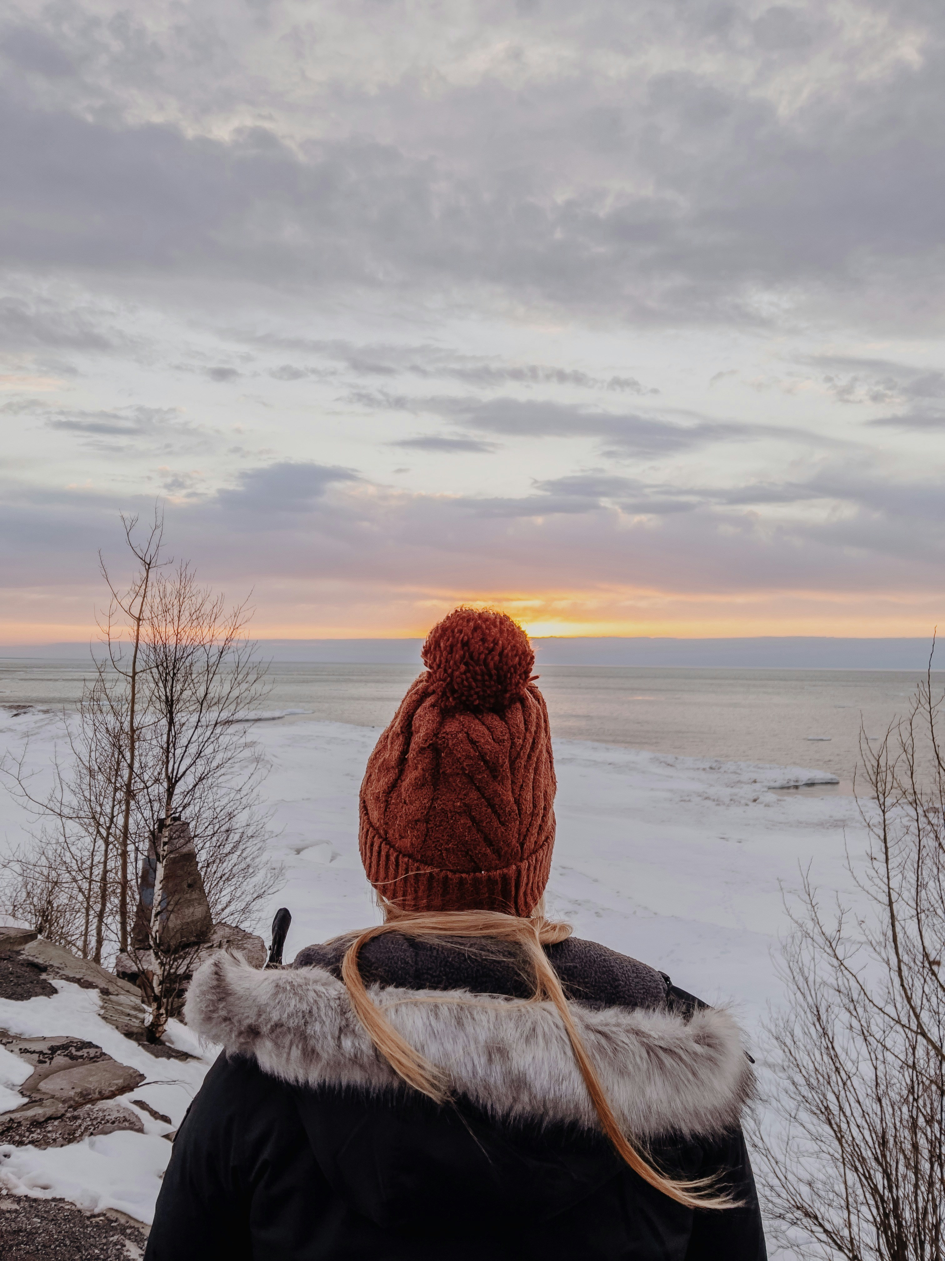 person in brown fur coat sitting on snow covered ground during daytime
