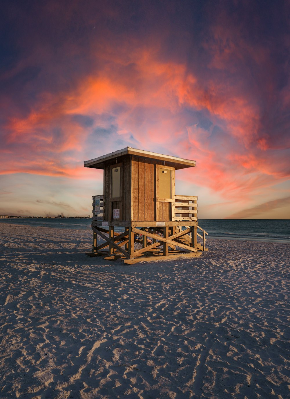 casa di bagnino in legno marrone sulla riva della spiaggia durante il tramonto