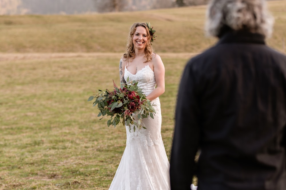 mulher no vestido de noiva branco que segura o buquê das flores