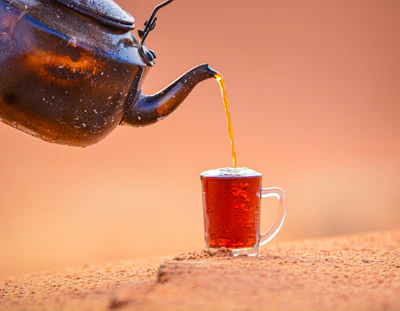 A steaming cup of herbal tea served in hand-painted pottery against a backdrop of desert mountains.