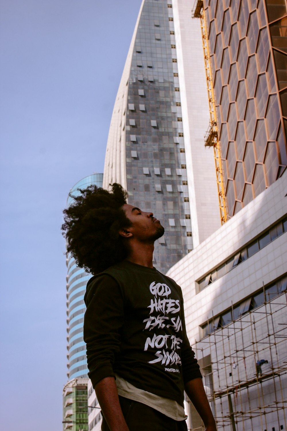 man in black and white crew neck shirt standing near white concrete building during daytime