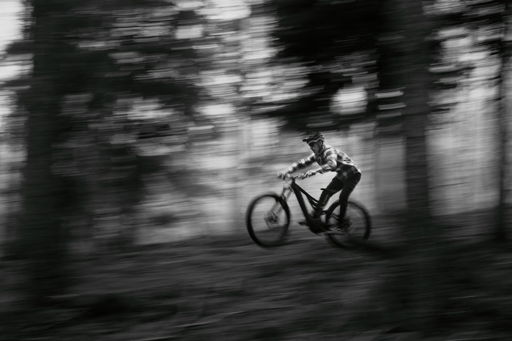 grayscale photo of man riding bicycle