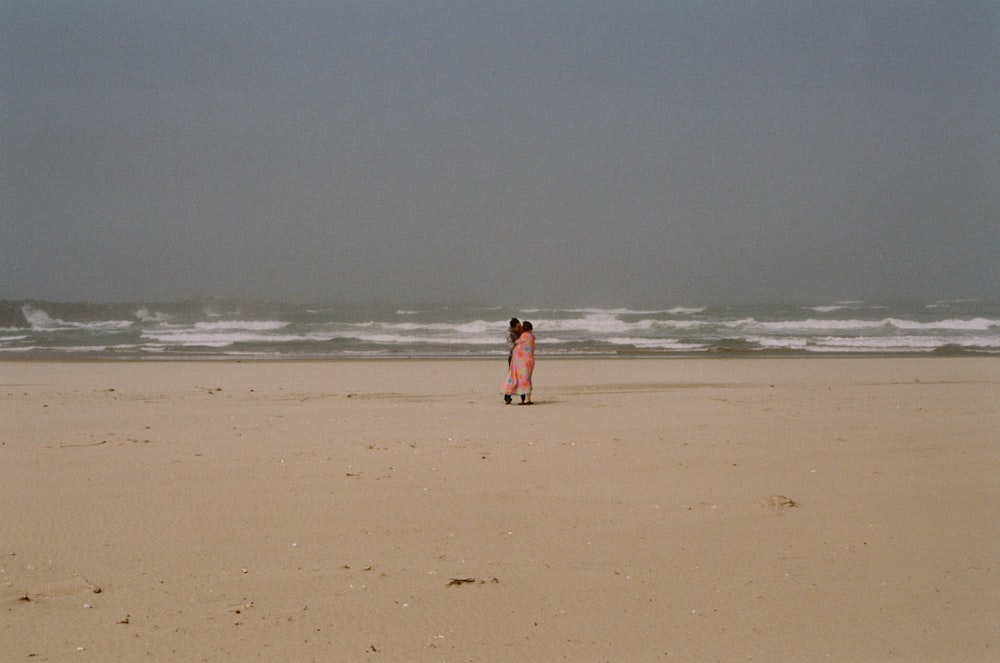 woman in red dress walking on beach during daytime