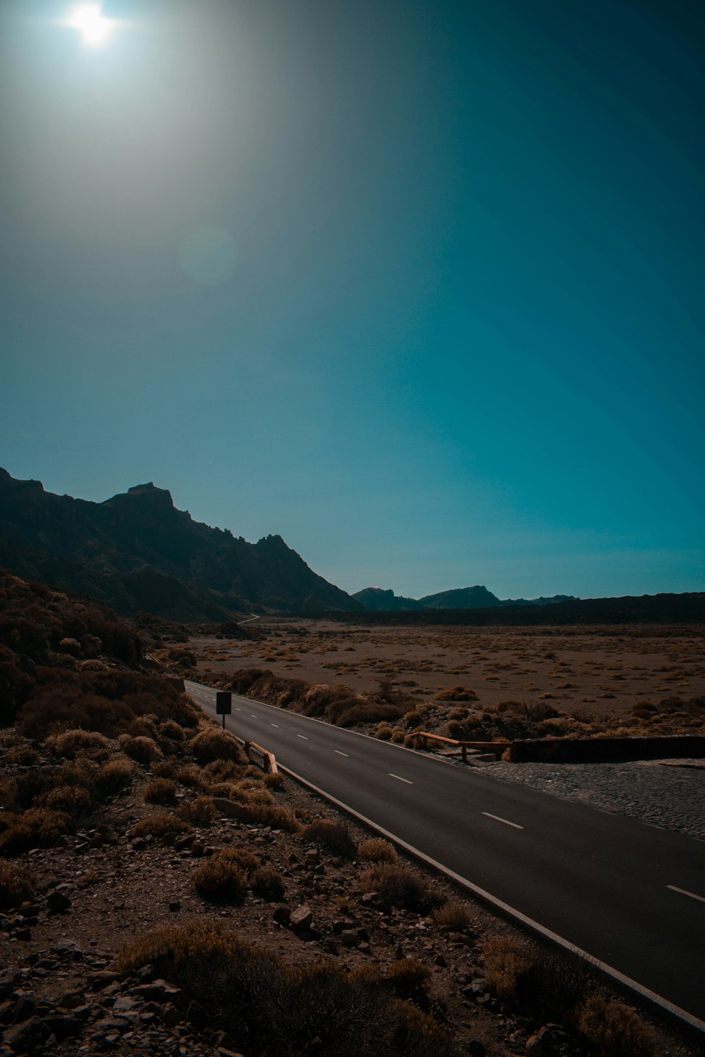 gray asphalt road near brown mountains during daytime