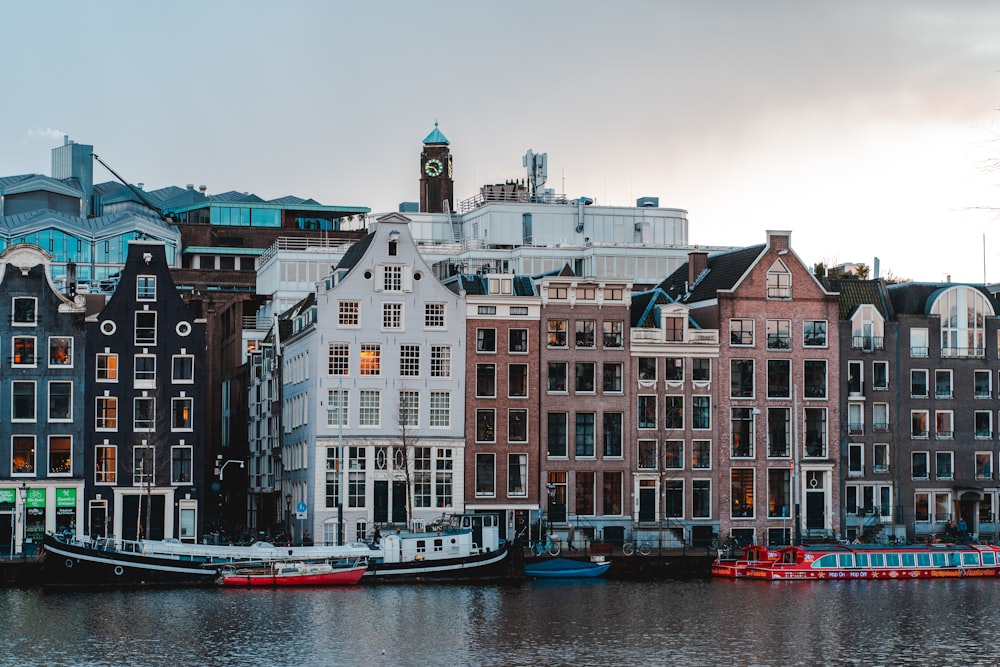 white and blue boat on body of water near concrete buildings during daytime